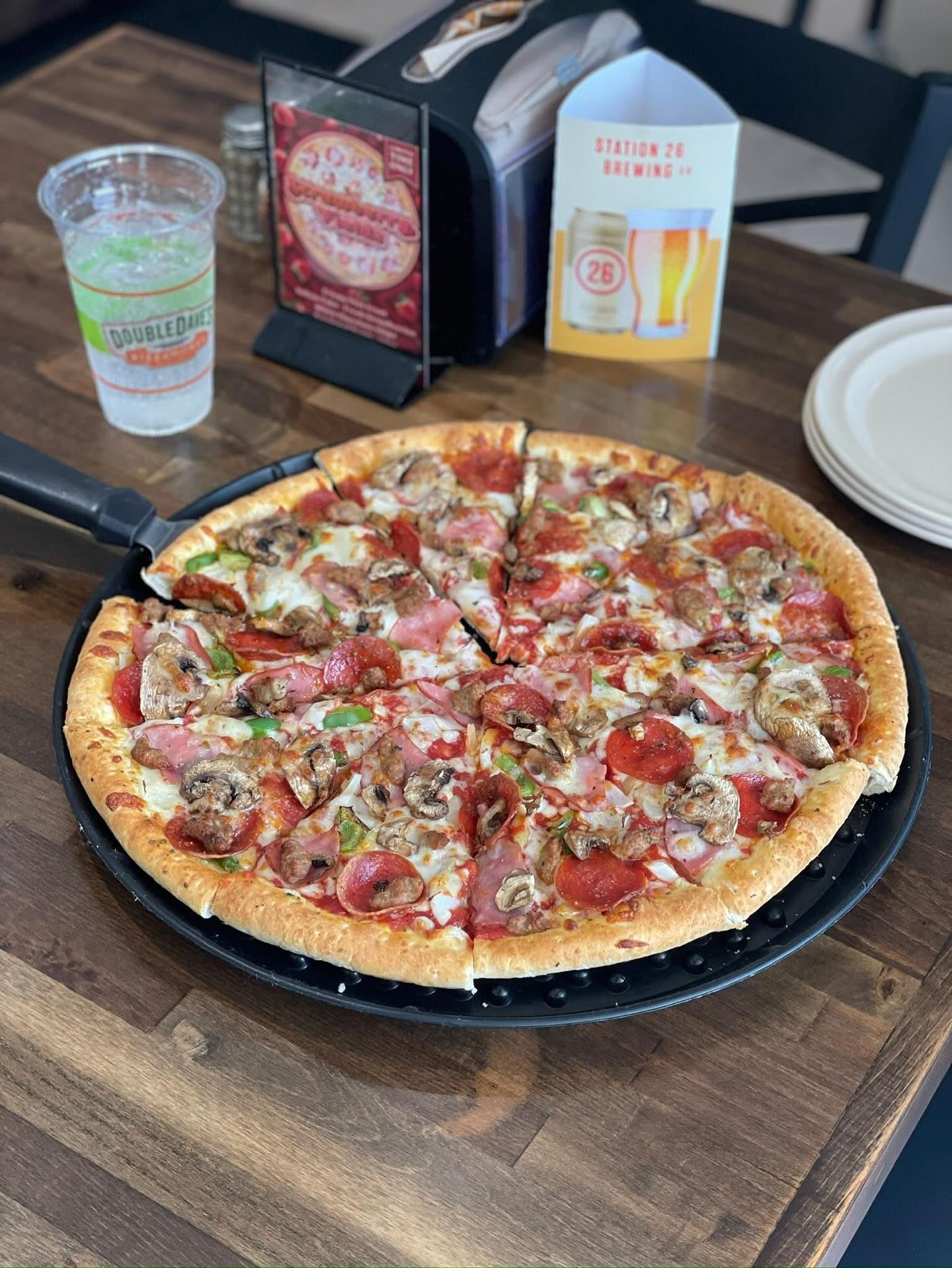 Sliced pizza with pepperoni, mushrooms, and ham on a table.