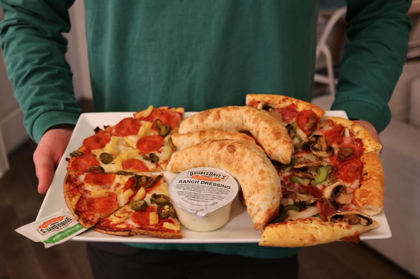 Person holds a tray of Double Dave's pizza, pizza rolls, and ranch.