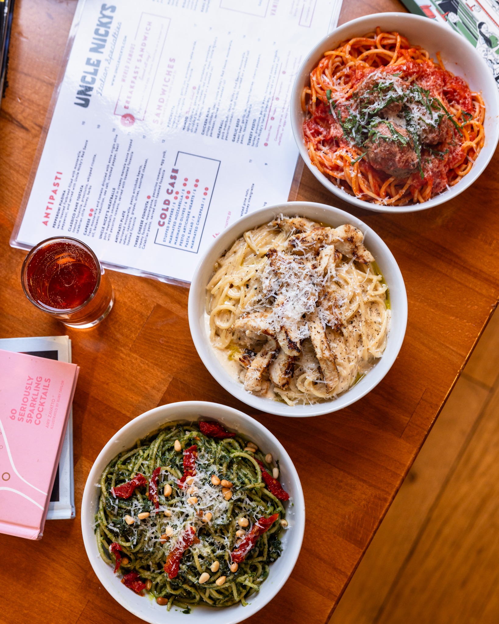 Three different pasta dishes, an Italian menu, and a drink.