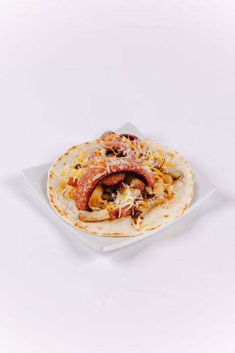 Tortilla with sliced sausage, shredded cheese, and cooked vegetables.