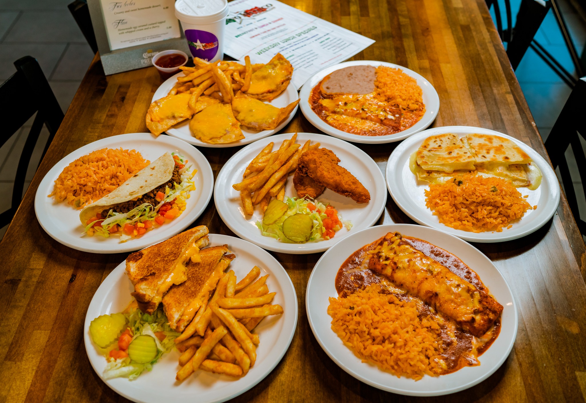 Multiple plates of Mexican-American dishes including tacos, quesadillas, and fries.