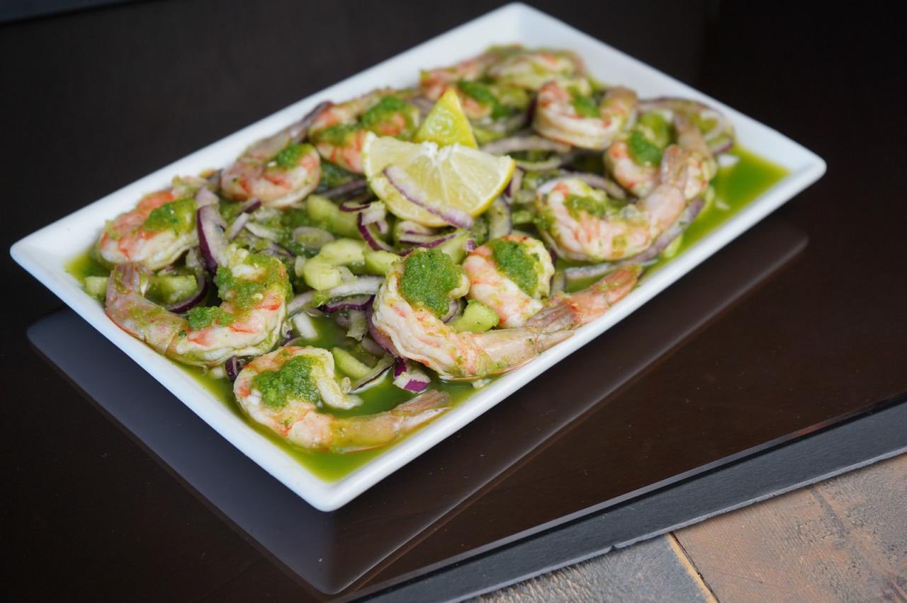 Shrimp with green sauce, red onion, cucumber slices, and lemon.
