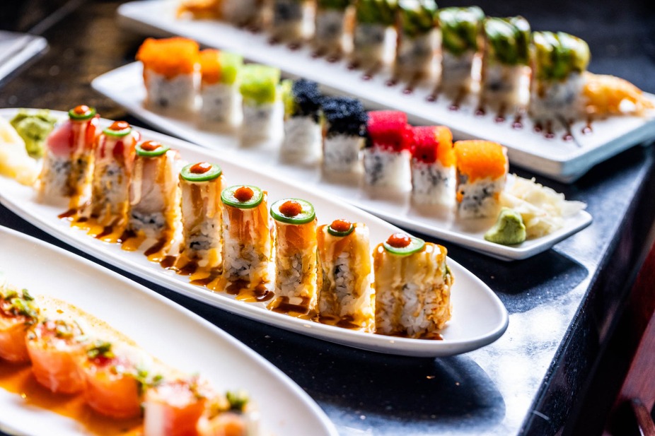 Multiple platters of colorful sushi rolls with diverse toppings.