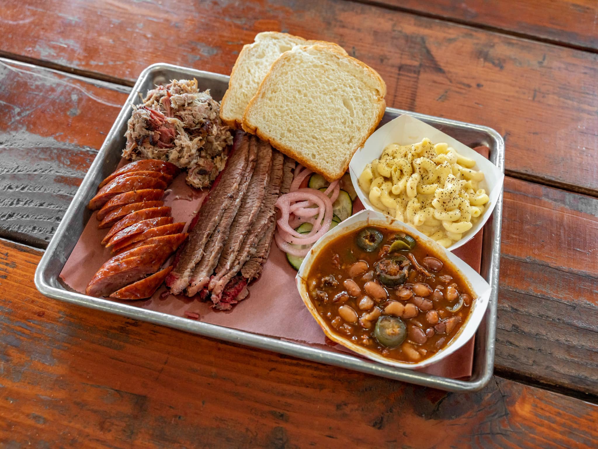 Assortment of BBQ meats, mac and cheese, baked beans, and bread.
