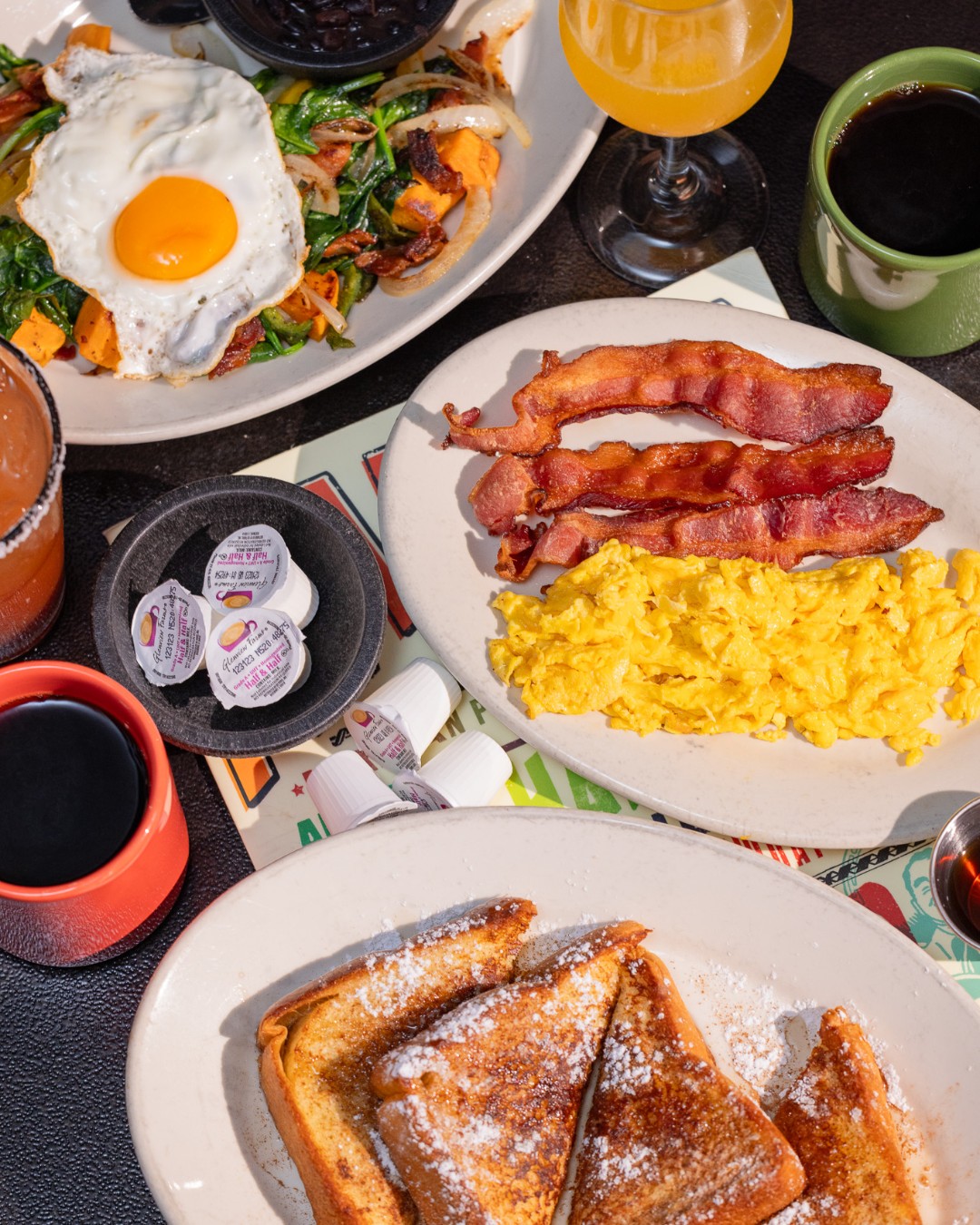 Breakfast spread with eggs, bacon, French toast, coffee, and orange juice.