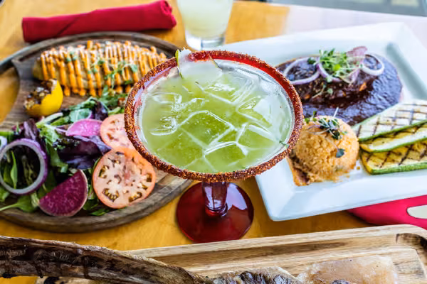 Green drink, salad, and entrees served on a restaurant table.
