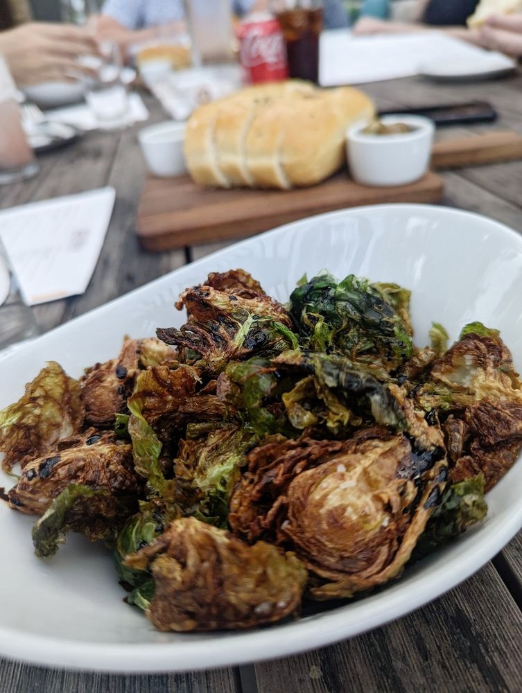 Roasted brussels sprouts in a white bowl on a wooden table.