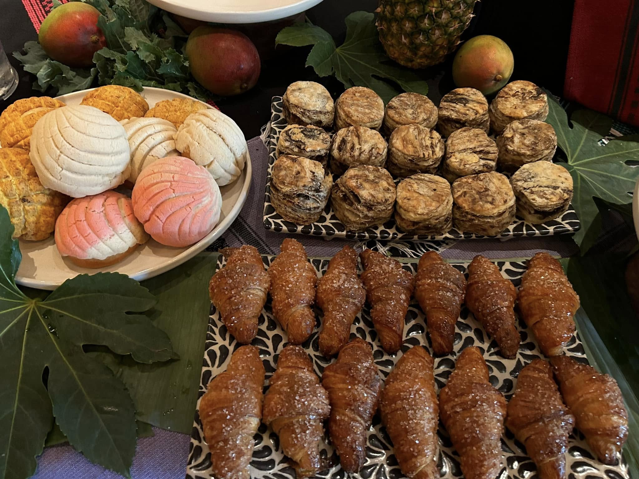 Plates of conchas, layered pastries, and sugar-dusted croissants.
