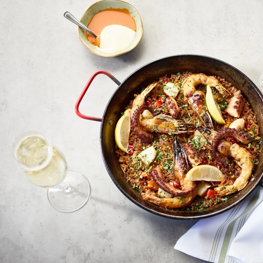 Seafood rice dish with shrimp, octopus, lemon, sauces, and sparkling wine.