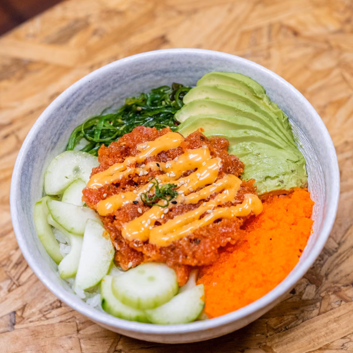 Rice bowl with chopped fish, avocado, seaweed, cucumber, and fish roe.