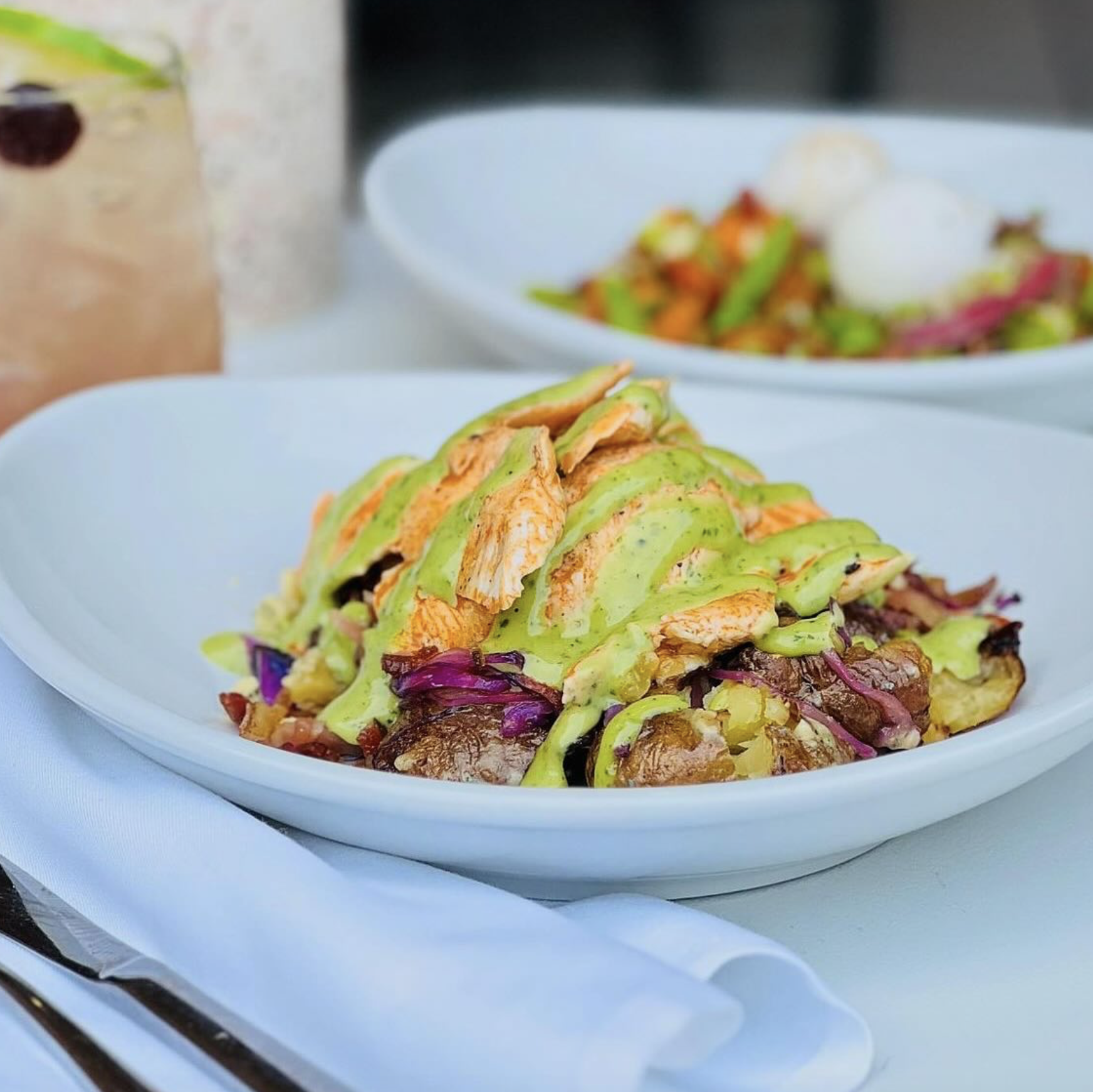 Plate with chicken, green sauce, roasted potatoes, and red cabbage.