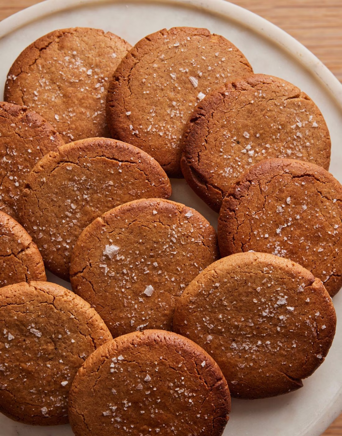 A platter of round brown cookies topped with white flaky salt.