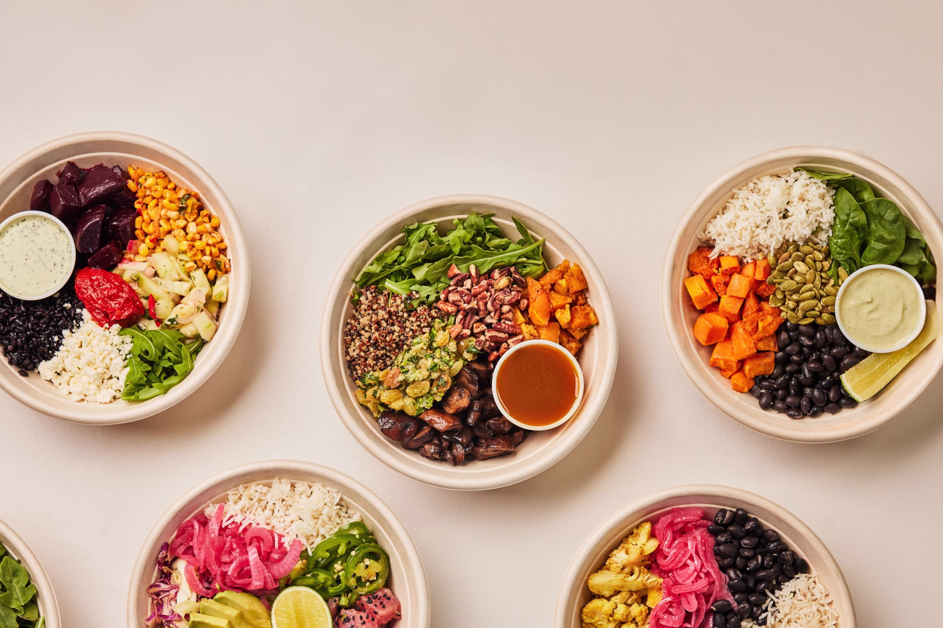 Variety of colorful food bowls with grains, vegetables, and sauces.