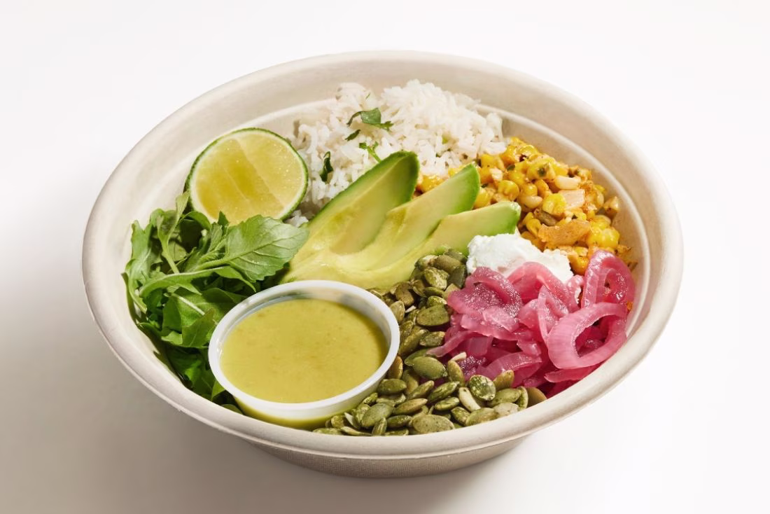 Bowl of rice, avocado, corn, pickled onions, greens, and dressing.