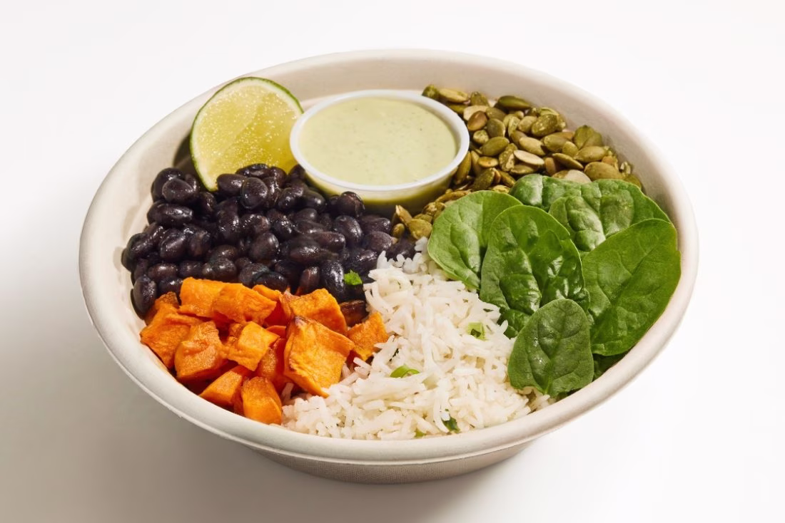 Bowl with black beans, rice, sweet potato, spinach, pepitas, lime, sauce.