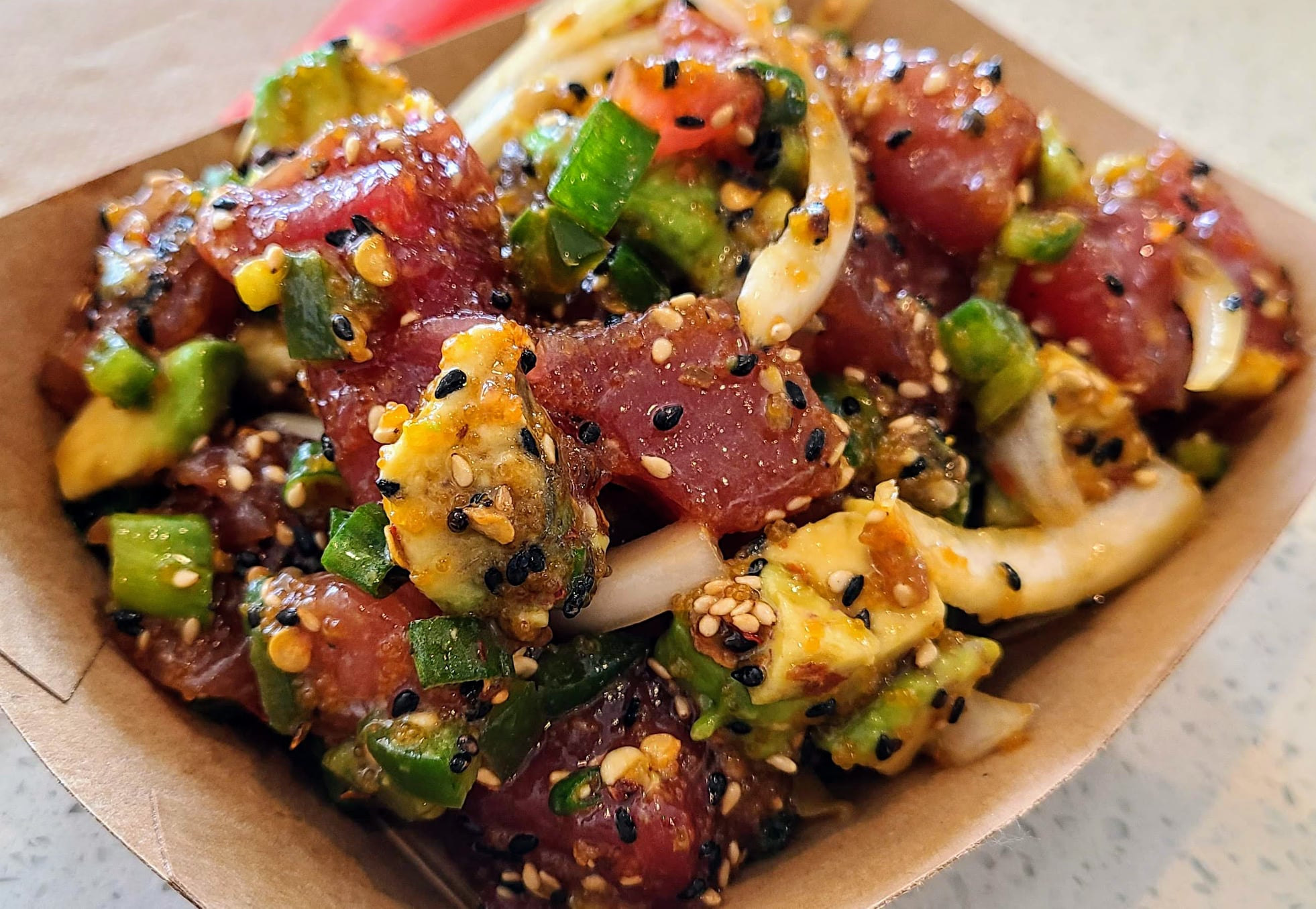 Close-up of tuna poke with avocado, onions, and sesame seeds.