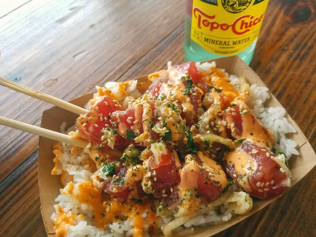 Poke bowl with rice, chopsticks, and a bottle of Topo Chico.