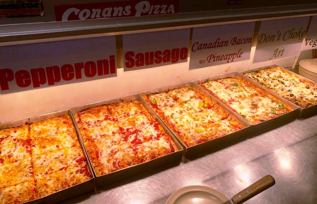 Conans Pizza buffet line with multiple trays of various pizzas.