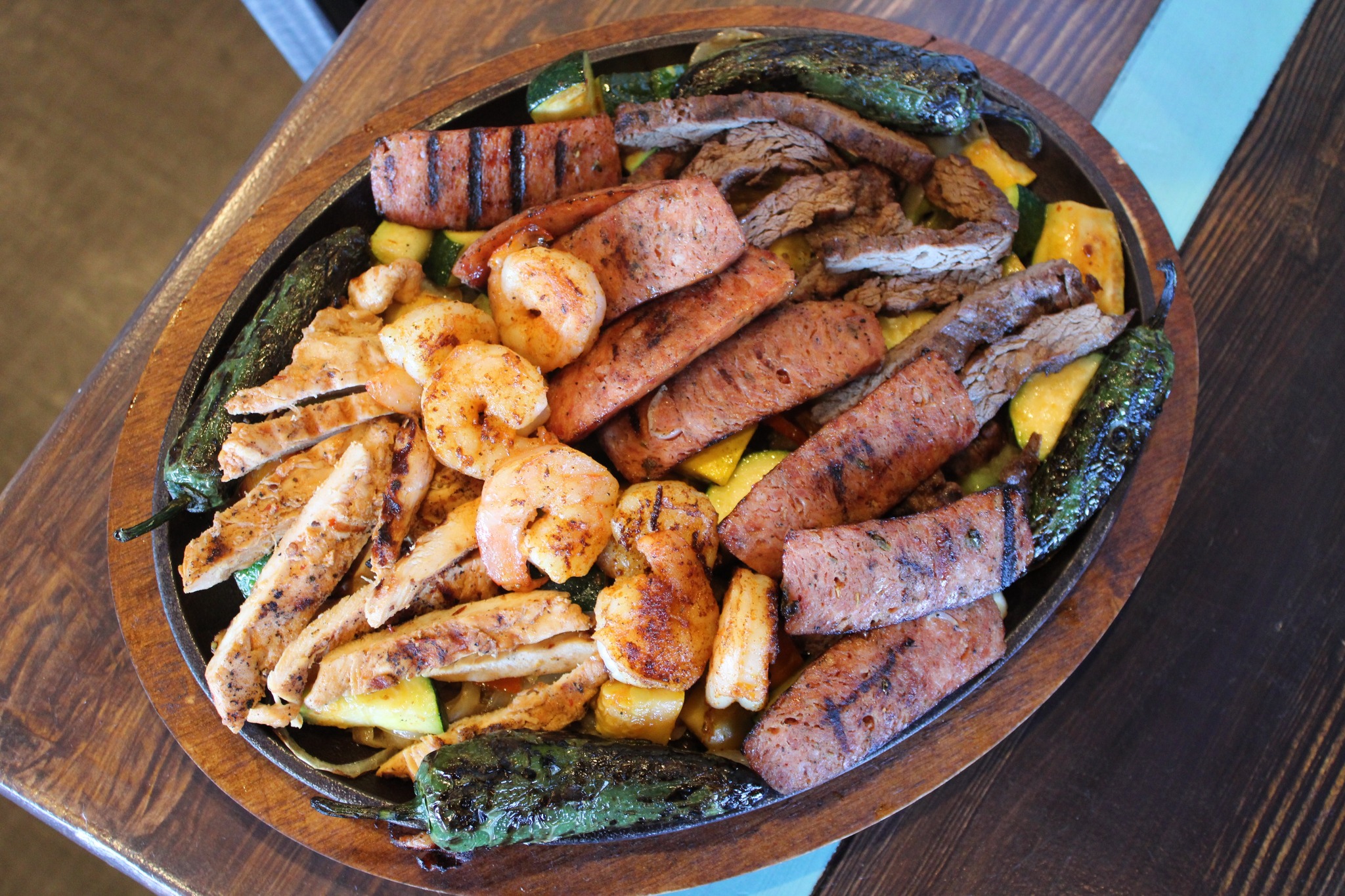 Grilled chicken, steak, sausage, shrimp, peppers, and zucchini on a platter.