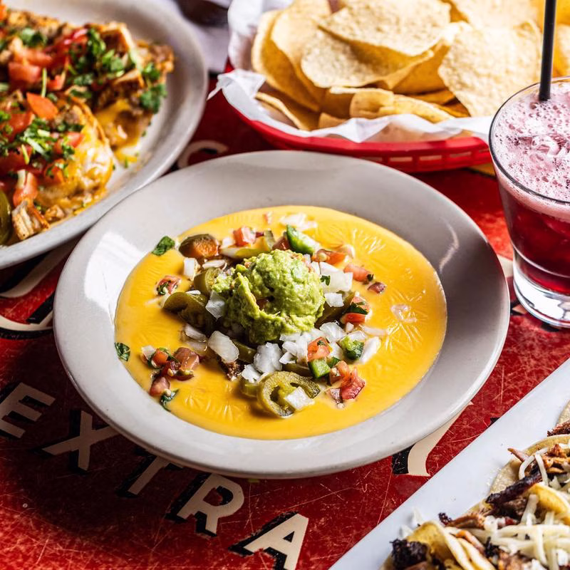 Queso dip topped with guacamole, jalapeños, and pico de gallo.