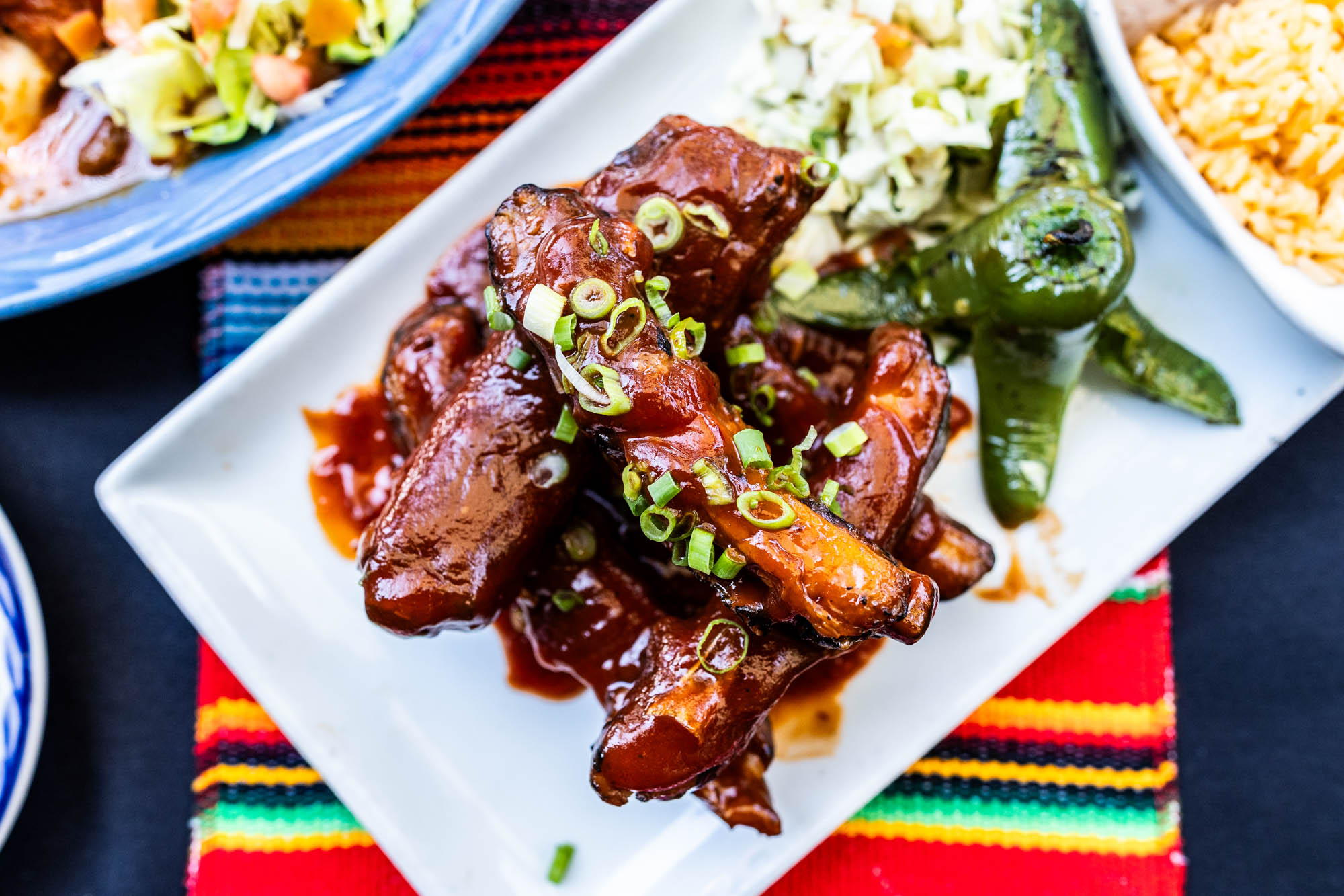 Plate of glazed meat with green onions, peppers, and rice.