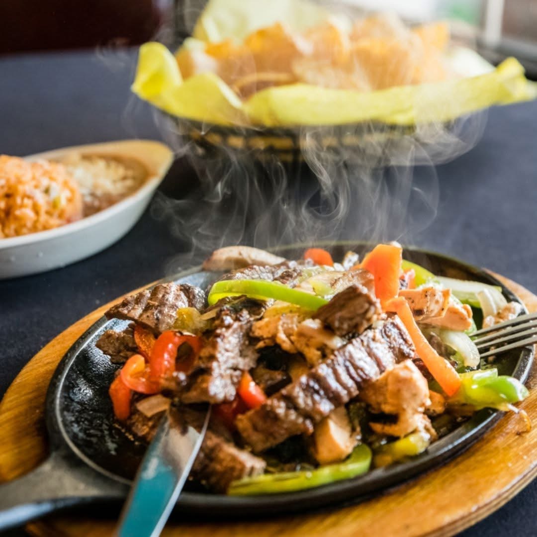 Steaming beef fajitas on a hot skillet with peppers and onions.