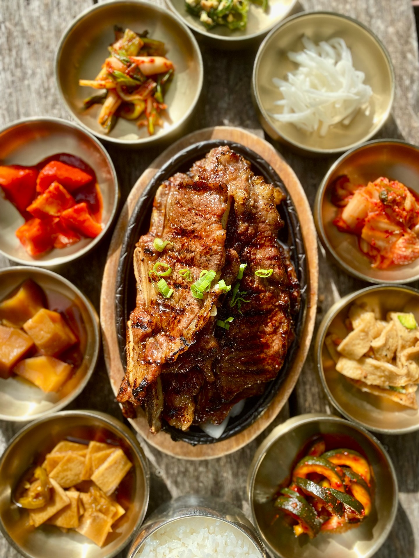 Overhead view of grilled beef short ribs, Korean banchan, and rice.