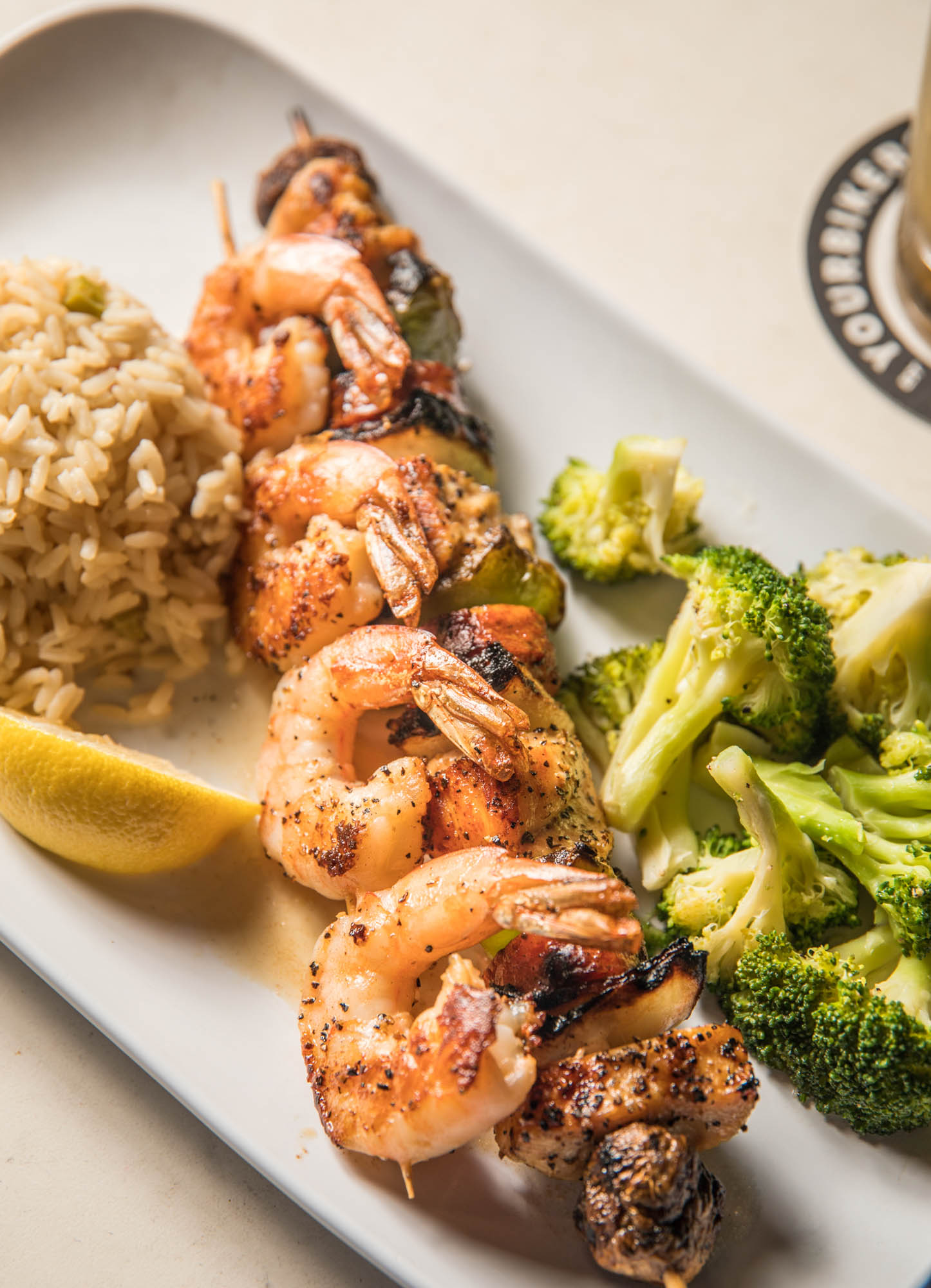 Grilled shrimp and chicken skewer, brown rice, broccoli, lemon wedge.