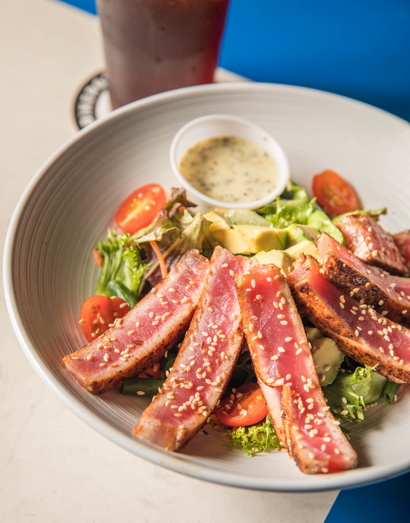 Seared tuna steak salad with mixed greens, avocado, and cherry tomatoes.