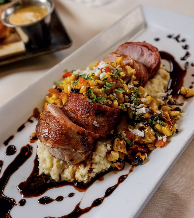 Sliced pork and corn salsa on mashed potatoes with sauce.