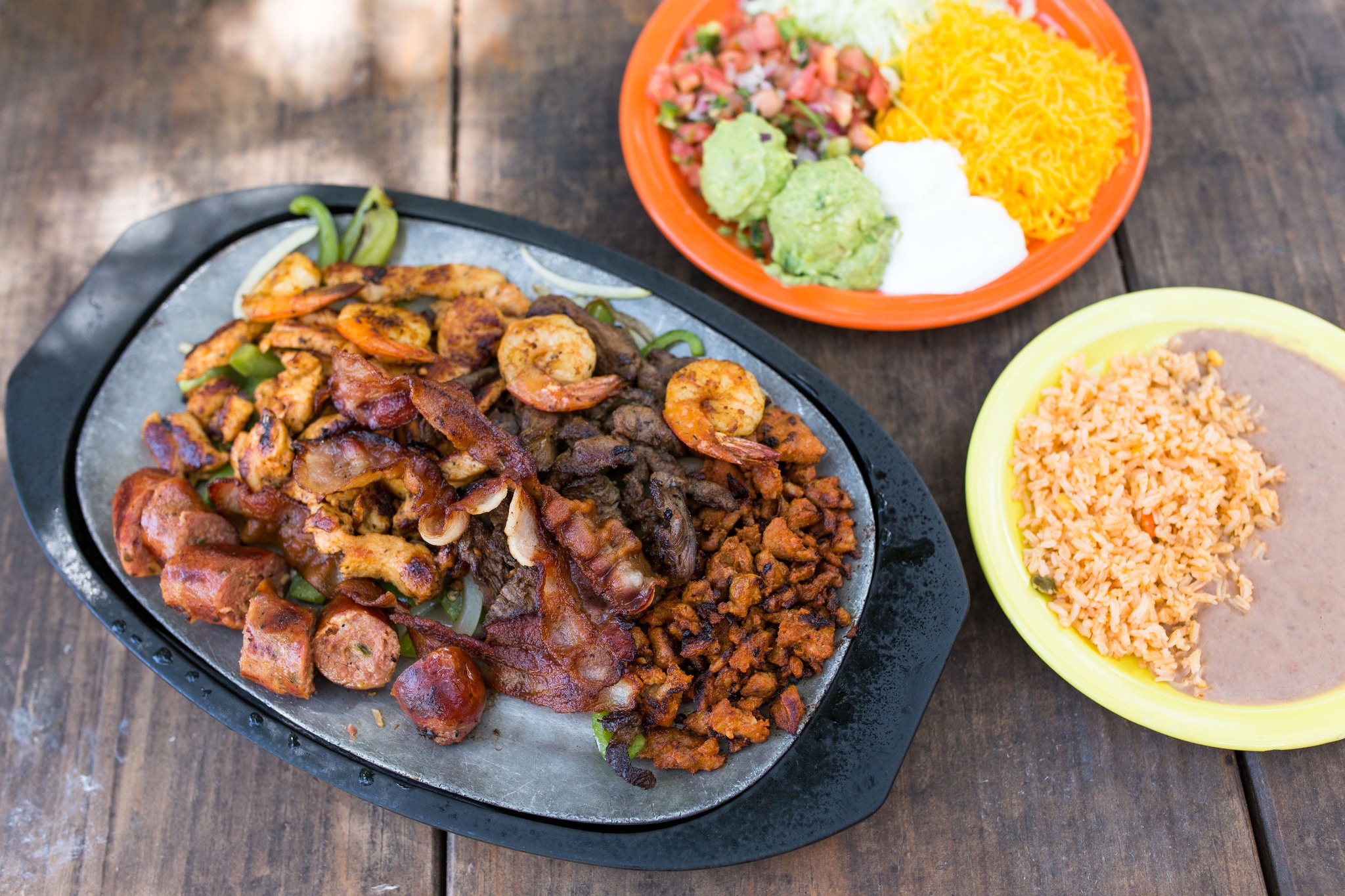 Mixed grilled meats, shrimp, and chorizo on hot platter with sides.