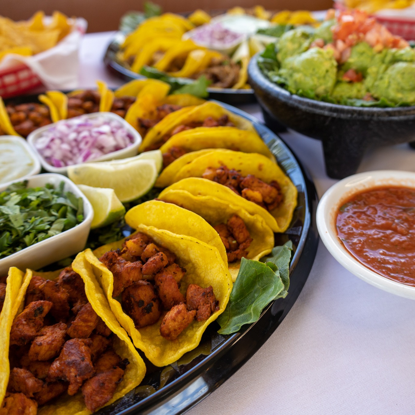 Assortment of tacos, guacamole, salsa, and fresh garnishes.