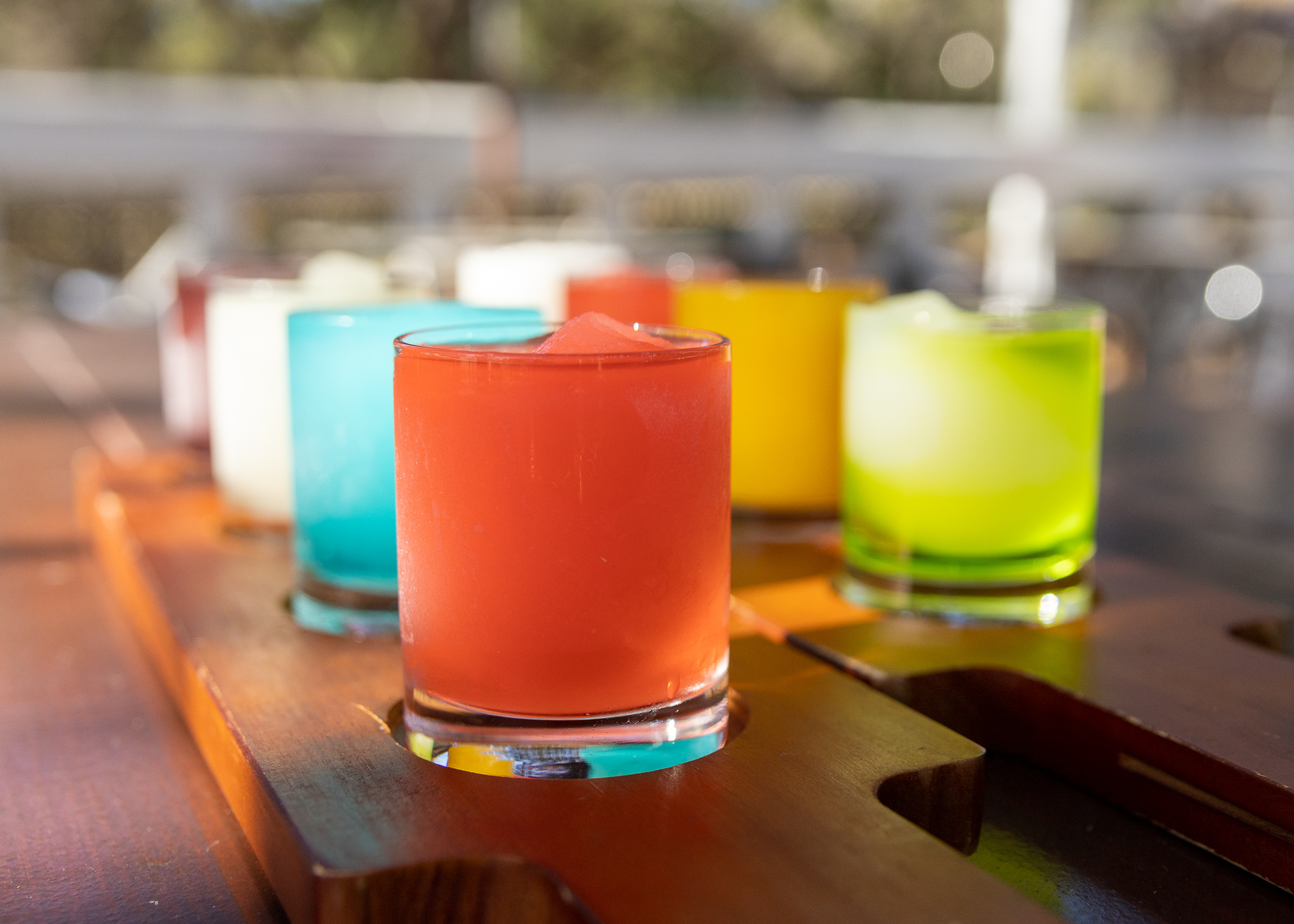 Colorful frozen drinks on a wooden flight board.