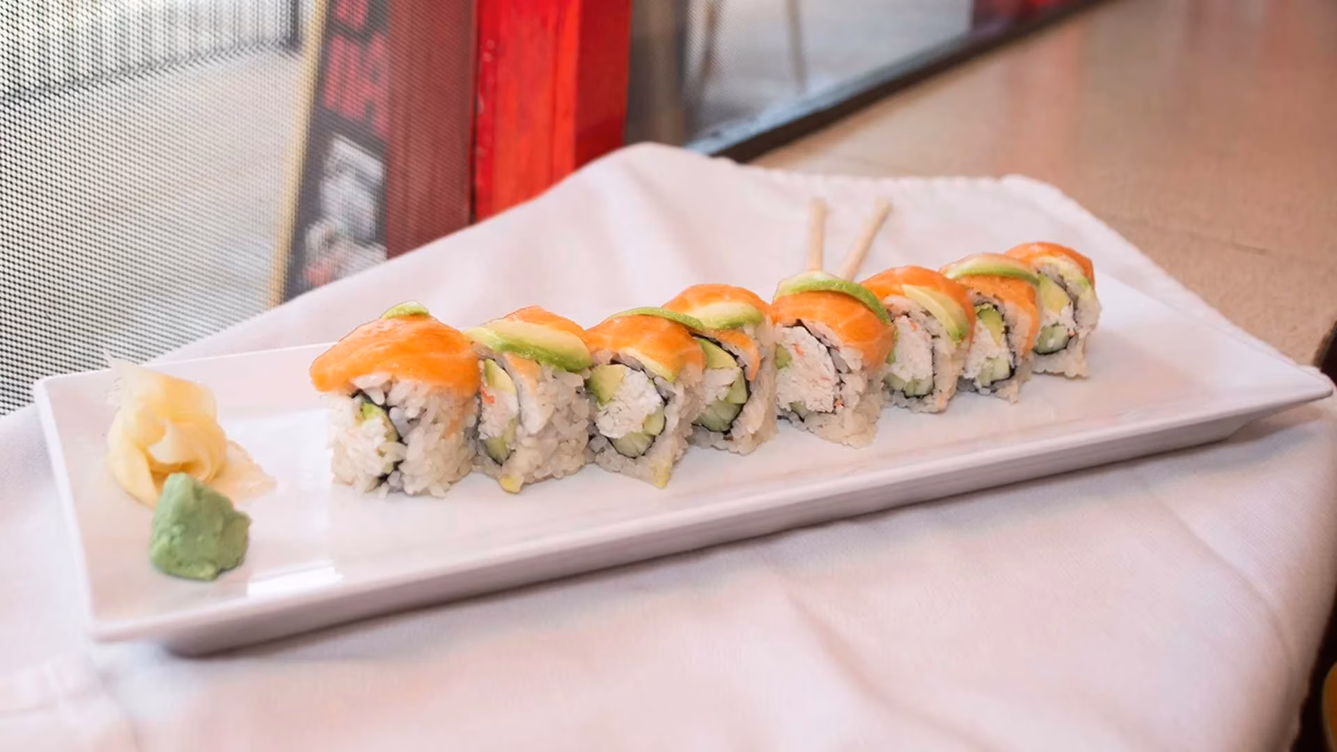 Plate of salmon and avocado sushi rolls with ginger and wasabi.