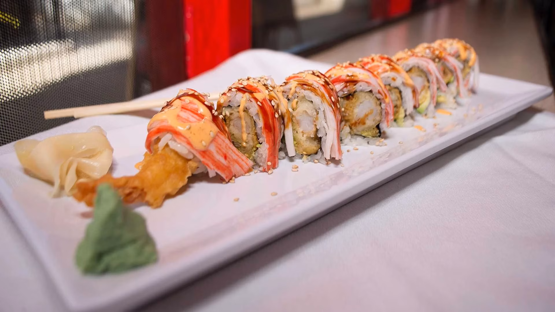 Sushi rolls with tempura shrimp, crab sticks, sauce, ginger, and wasabi.