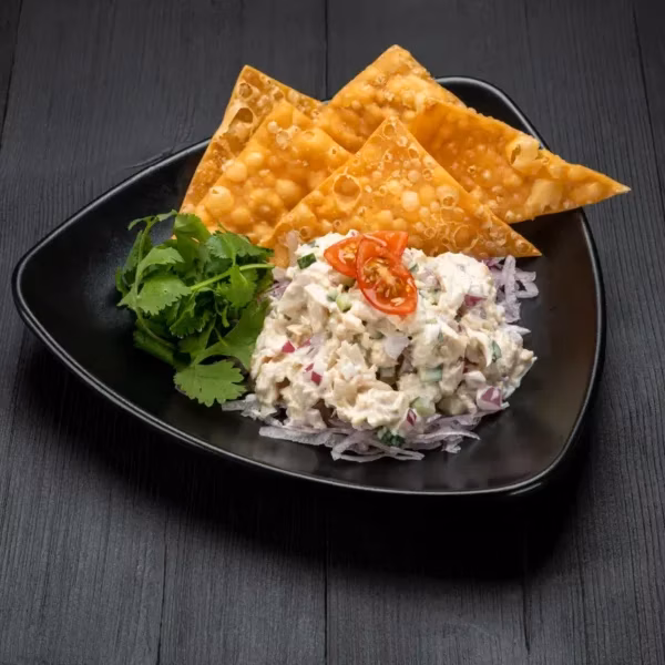 Chunky white salad with red onion, tomato, cilantro, and golden chips.