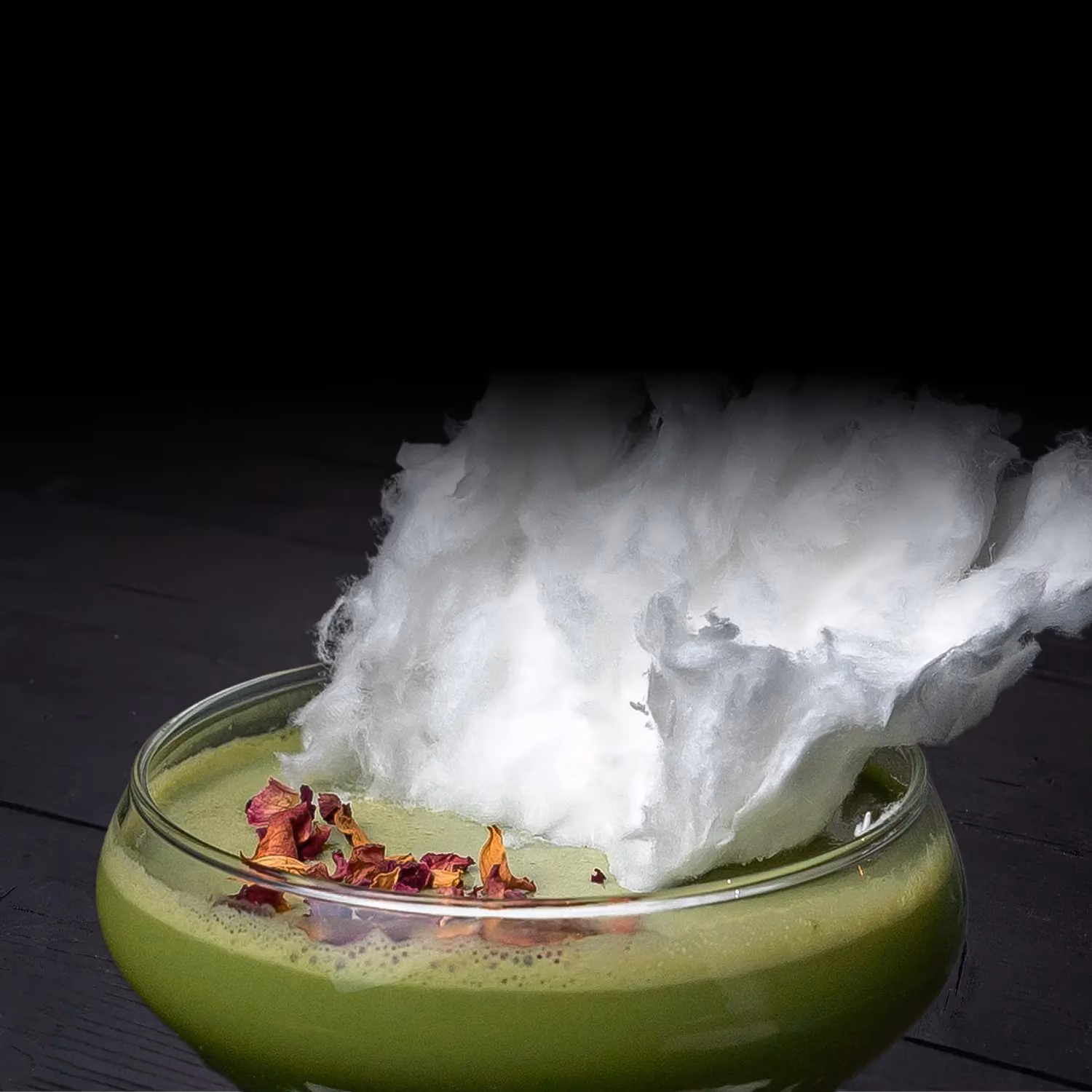 Close-up of green drink with cotton candy and dried flower petals.