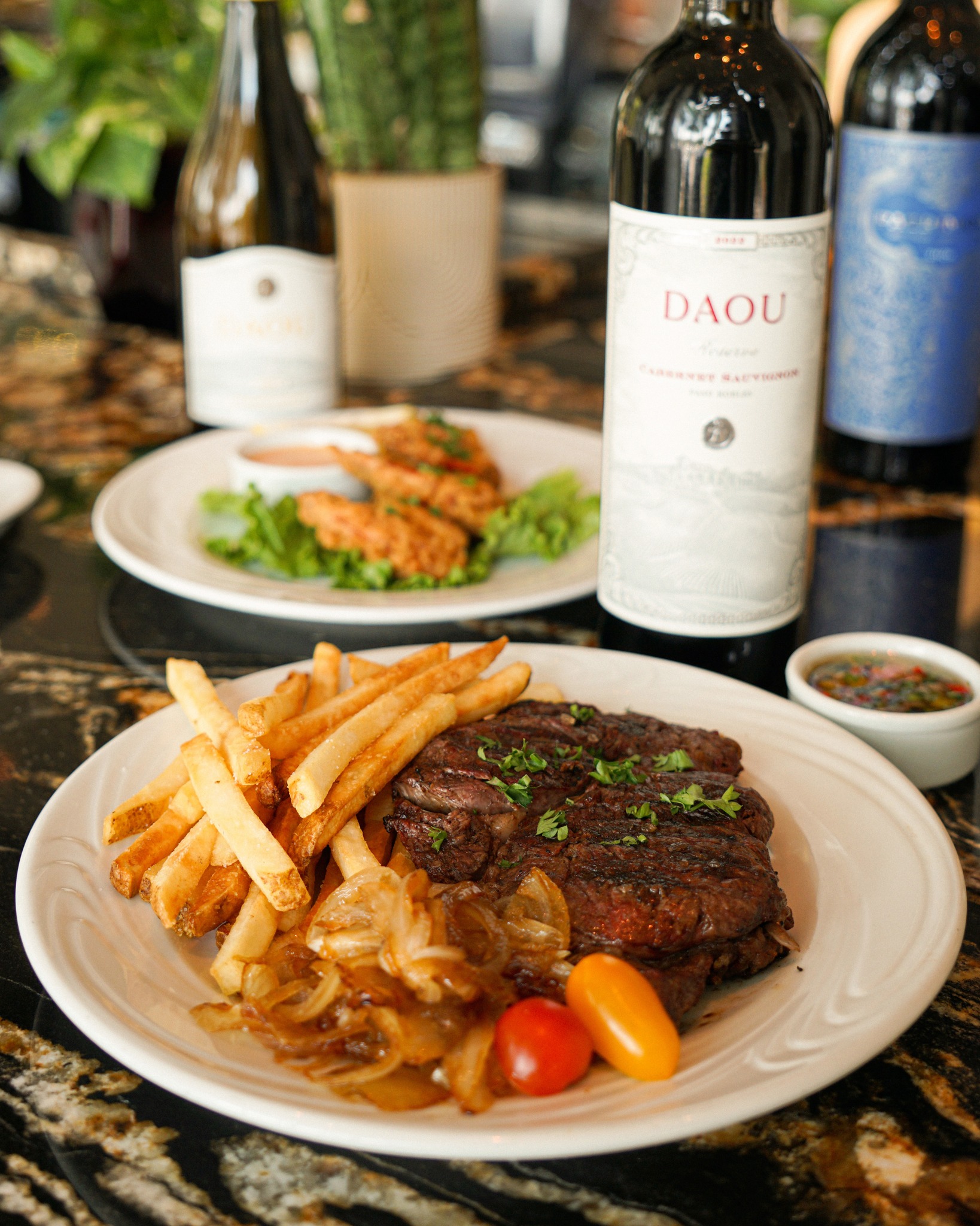 Grilled steak, fries, onions, and a DAOU wine bottle.