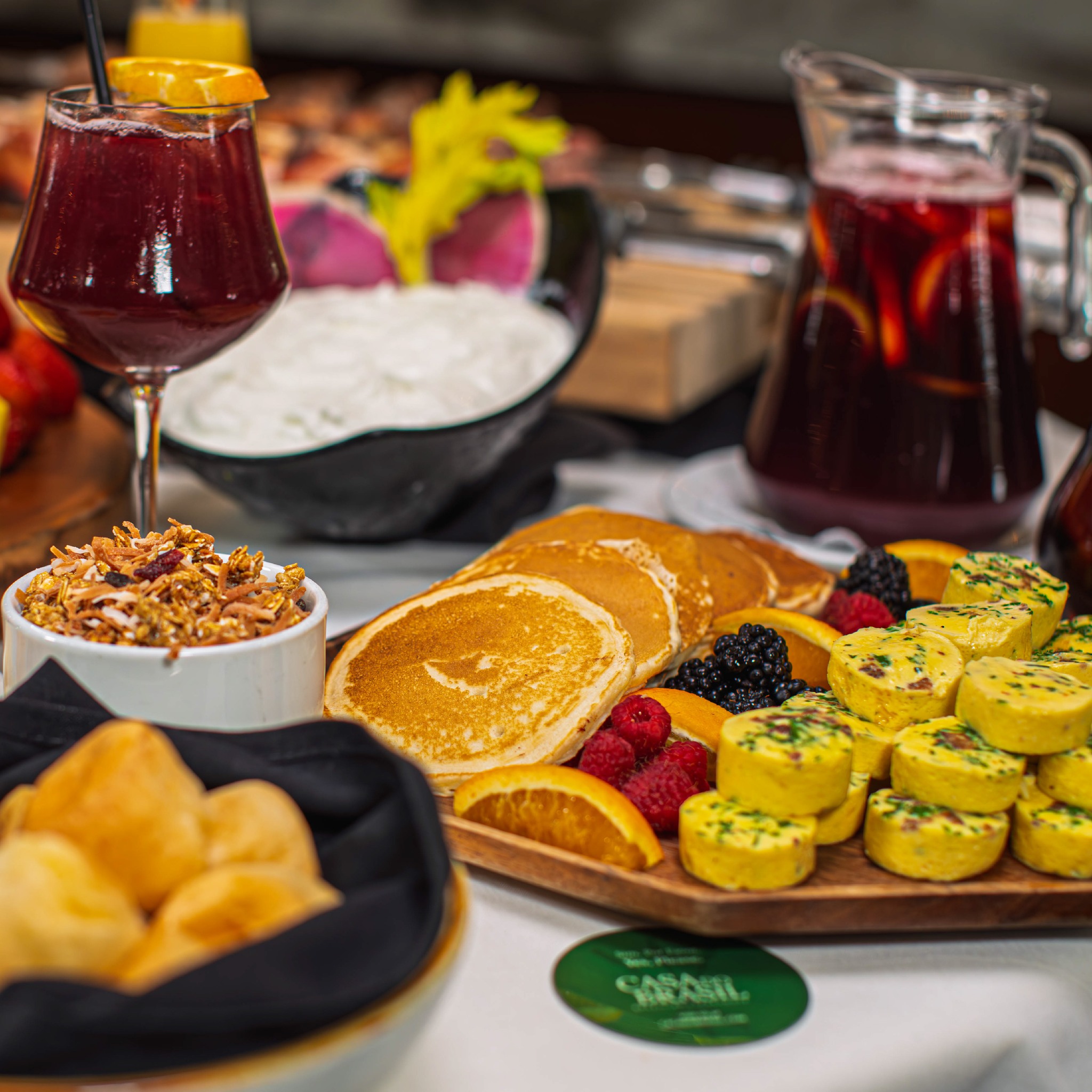 Breakfast buffet with pancakes, egg bites, berries, granola, and beverages.