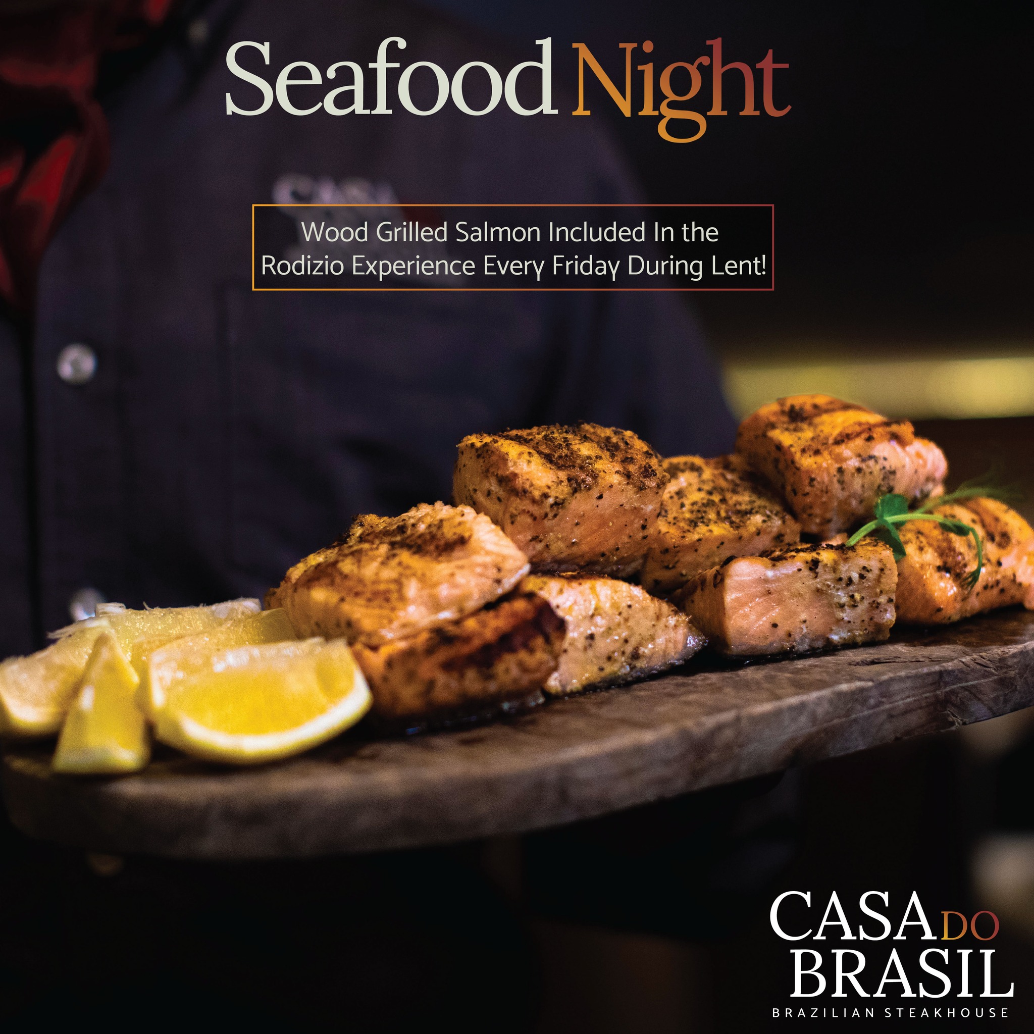 A server presenting wood-grilled salmon with lemon wedges.