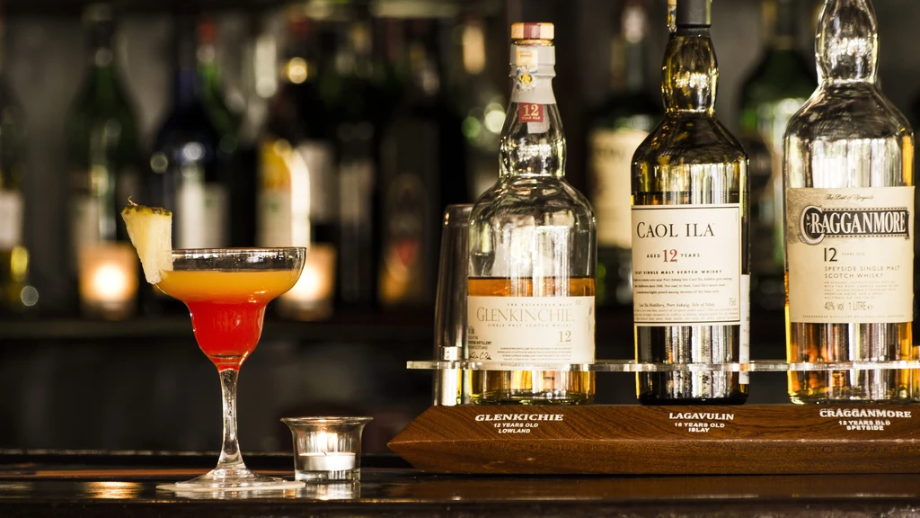 Martini cocktail, lit candle, and three single malt scotch whisky bottles.