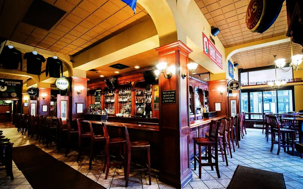 Empty, traditional pub with wooden bar, liquor bottles, and branded signs.