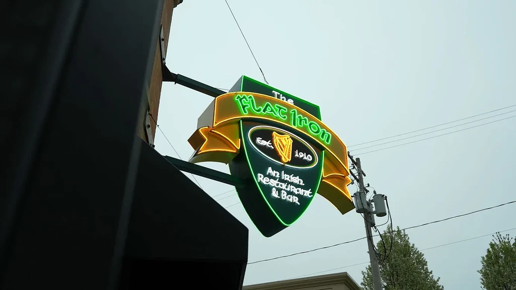 Green and gold shield neon sign for The Flat Iron Irish Bar.