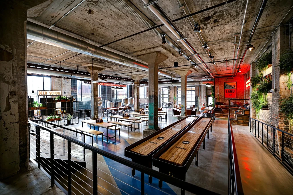 Industrial-chic brewery interior with shuffleboard tables and varied seating areas.