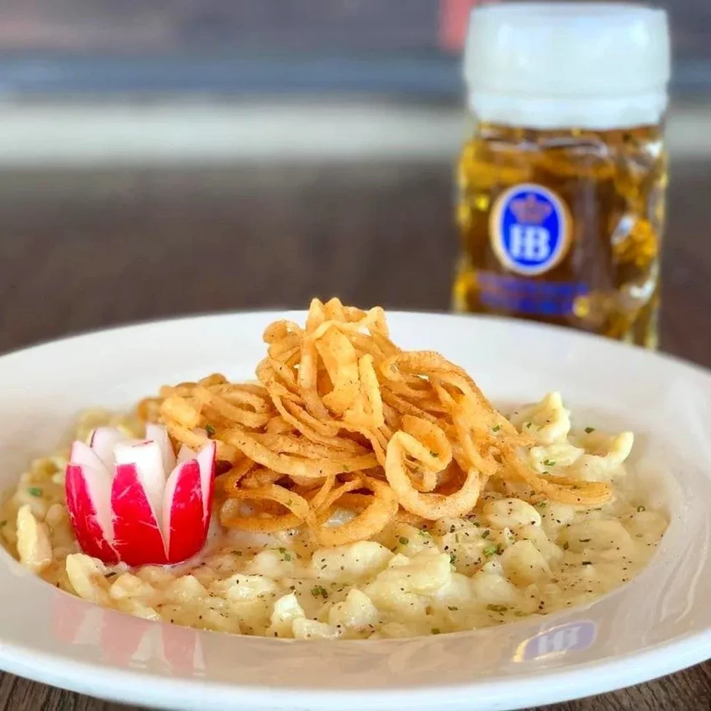 Creamy pasta dish with fried onions, radish, and a beer stein.