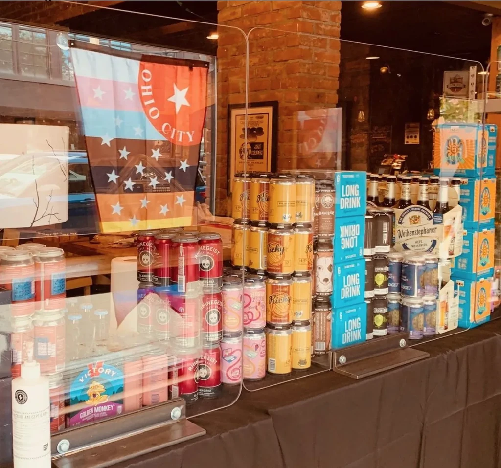 Colorful retail display of branded alcoholic cans and bottles behind glass.