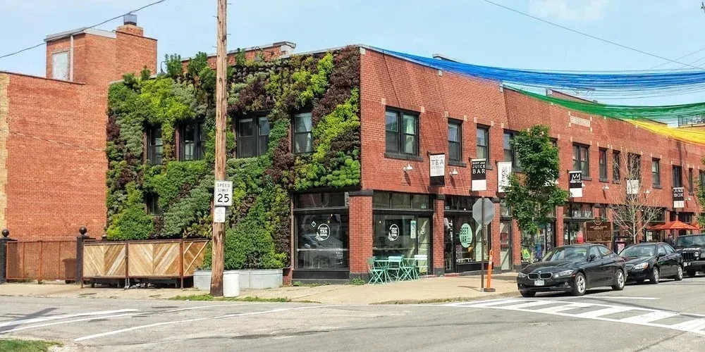 Multi-story brick building with a living wall and colorful street decor.