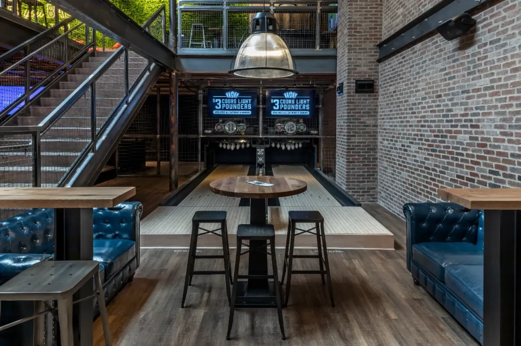 Boutique bowling alley interior with industrial decor and lounge seating.