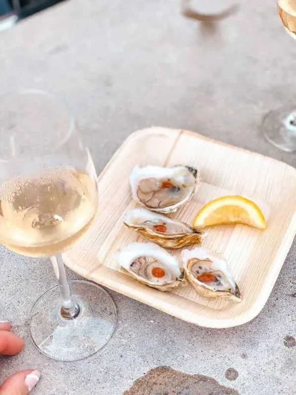 Four oysters with red topping, lemon, and sparkling wine.