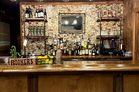 Well-stocked bar counter in a rustic restaurant interior, with liquor bottles.